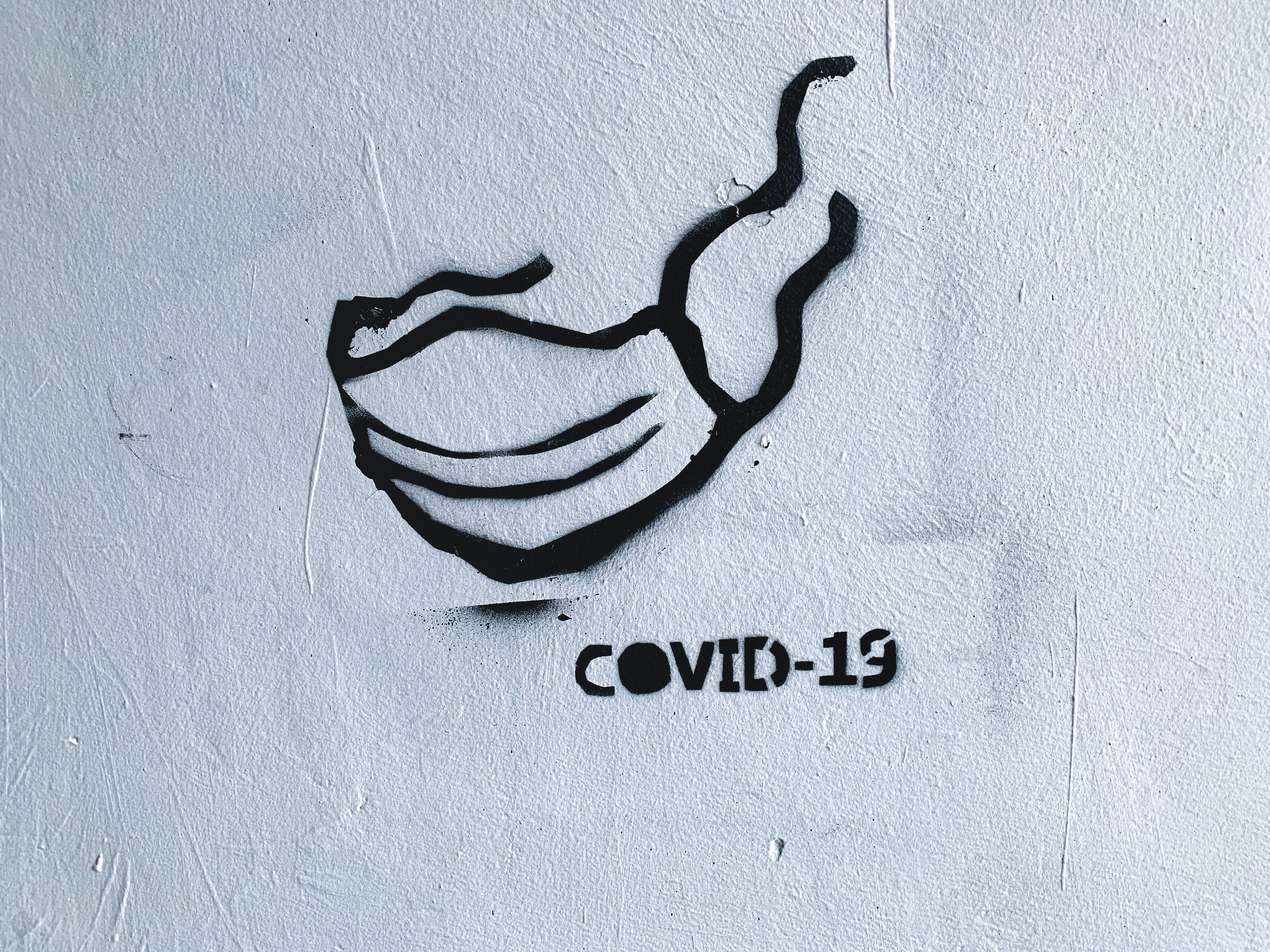 Street art of a black face mask with "COVID-19" writing